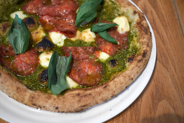 Pizza with salami, pesto and basil