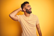 Young Indian Man Wearing T-shirt Standing Over Isolated Yellow Background Smiling Confident Touching Hair With Hand Up Gesture, Posing Attractive And Fashionable