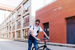 © Manuel Ruiz Alba/ADDICTIVE STOCK - Young smiling black successful man with Afro hair in casual outfit and stylish sunglasses standing with bicycle on street