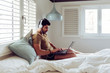 © Manuel Ruiz Alba/ADDICTIVE STOCK - Young concentrated successful man in casual shirt and headphones sitting on bed using a laptop computer