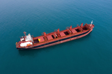 Aerial view of sea vessel for transportation of cargo vessel at high speed is drifting near the seaport of the city at sunset. Ship on the background of blue sea water. Import, export. Top