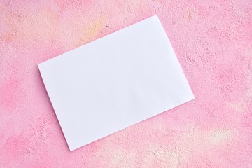 Wall Mural - Blank sheet of white paper for design banner or card on textured pink background, selective focus. Clear page with empty space for image or text on pink plaster backdrop. Mockup concept 