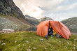 Spronser Lakes Hike, South Tyrol, Italy: A woman preparing instant food from inside her tent at the shore of the 
