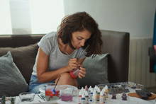  Brunette Woman Of Latin Race Painting Small Figures With A White Background.