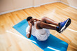 © twinsterphoto - Top view of young African American man doing sit-up exercise on yoga mat at gym. Male fitness model performing crunch at fitness center