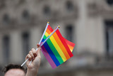 Fototapeta Tęcza - Spectators waves a gay rainbow flag at an LGBT gay pride community event