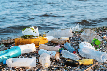 Wall Mural - Spilled garbage on the beach of a big city. Empty used dirty plastic bottles, children's plastic toys. Dirty sea, sandy coast the Black Sea. Environmental pollution. Ecological problem. Moving waves