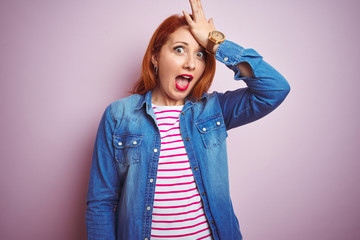 Sticker - Beautiful redhead woman wearing denim shirt and striped t-shirt over isolated pink background surprised with hand on head for mistake, remember error. Forgot, bad memory concept.