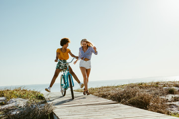 two women having fun with a bicycle at beach