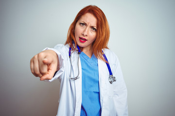 Sticker - Young redhead doctor woman using stethoscope over white isolated background pointing displeased and frustrated to the camera, angry and furious with you