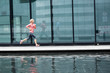 © Tandem Stock - European Quarter, Stuttgart, Baden-W¸rttemberg, Germany: A female runner running along the glass walls of an office building that shows her reflection.