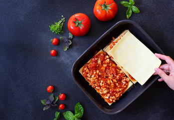 Recipe for homemade Italian lasagna with tomato sauce and meat. Phased recipe. Cooking lasagna. Place noodles on top. Two portions. Dark background. Top view. Copy space