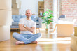 © Krakenimages.com - Young bald man sitting on the floor around cardboard boxes moving to a new home happy face smiling with crossed arms looking at the camera. Positive person.