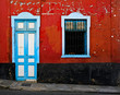 Colorful grungy wall and door, architecture detail, red wall with blue door and window, Latino district.