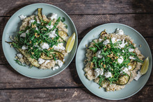 Two Plates Of Lemon Risotto With Buffalo Mozzarella, Rocket, Baked Courgette And Pine Nuts