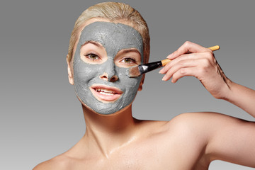 Wall Mural - Beautiful Woman Applying Clay Facial Mask. Beauty Treatments. Spa Girl Apply Clay Facial mask with Beauty Brush