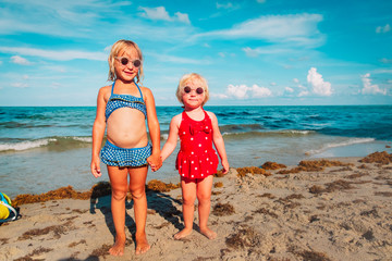 happy cute little girls play with water on beach