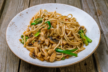 Sticker - Udon noodles with chicken and vegetables on wooden background