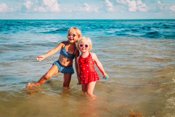 happy cute little girls play with water on beach