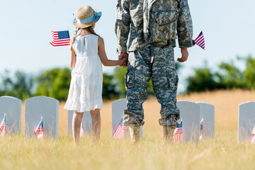 Canvas Print - Cropped view of military man and patriotic child holding hands and American flags