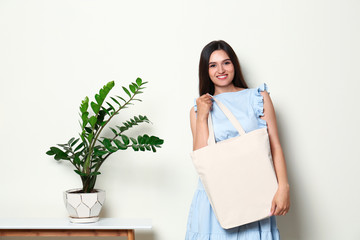 Wall Mural - Beautiful young woman with stylish blank eco bag near white wall