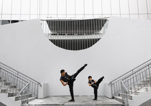 Father And Son Are Engaged In Wushu In The City. The Photo Illustrates A Healthy Lifestyle And Sport. The Father Trains The Son.