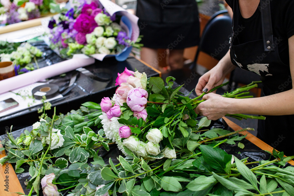Female florist create a bouquet at workplace. Floristics workshop. Making beautiful flower bouquets and floral decorations.. - obrazy, fototapety, plakaty 