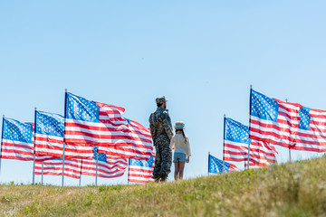 Wall Mural - man in military uniform standing with daughter near american flags