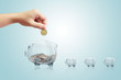 Hand puts a coin in the piggy bank on isolate background.Inserting a coin into a piggy bank