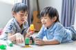 funny two boys playing with colourful cup toys on floor.Asian little boys playing stack cup at home