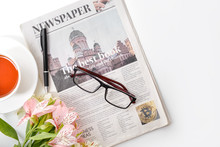 Newspaper, Flowers And Cup Of Tea On White Background