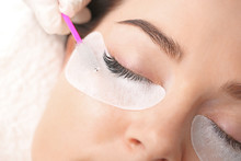 Young Woman Undergoing Eyelash Extension Procedure In Beauty Salon, Closeup