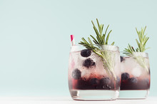 Fresh Arctic Liquors With Ice Cubes, Blueberry, Rosemary, Straw In Two Glasses On White Wood Table And Pastel Green Wall, Copy Space.