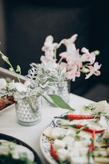 Wall Mural - Stylish floral decor on wedding table. White eustoma and orchid flowers in glass and delicious appetizers on wedding centerpiece. Luxury catering and adorning