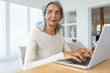 © wavebreak3 - Woman using white laptop on a table.