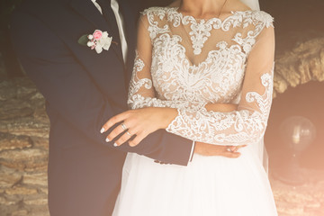 Wall Mural - Groom and bride are hugging. Happy wedding couple photo. Romantic photoshoot. White dress with long sleeves. Lace veil.