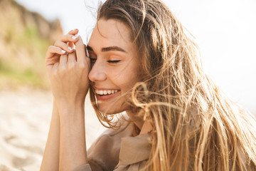 Wall Mural - Young cheery happy pleased gorgeous attractive woman lies outdoors at the sea beach.