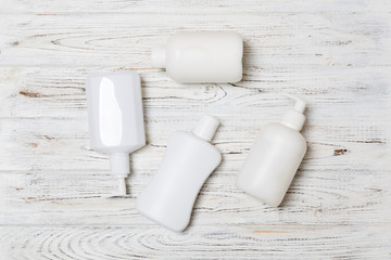 Set of White Cosmetic containers on wooden background, top view with copy space. Group of plastic bodycare bottle containers with empty space for you design