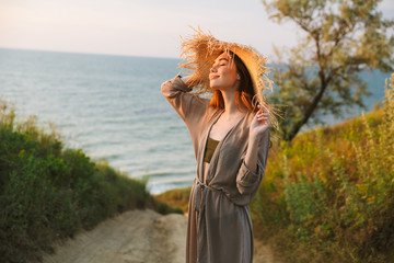 Wall Mural - Beautiful young pretty woman in hat posing outdoors near sea on the beach.