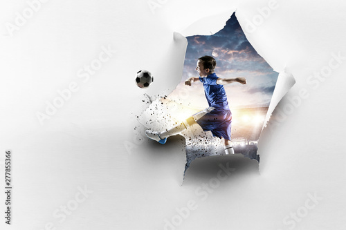 Fotografía Paper torn hole effect and a kid playing soccer. Mixed media
