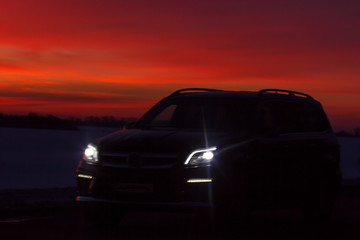 Wall Mural - silhouette of the car traveling on the road to a beautiful frosty sunset