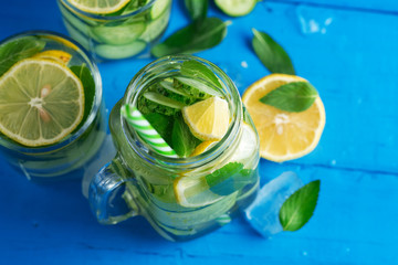 Detox wall-mounted cucumber water with lemon and mint on a wooden blue table