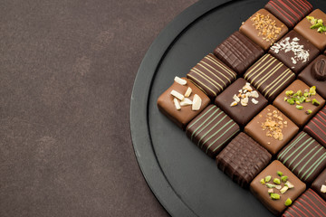 Wall Mural - chocolates variety in black tray on brown background