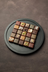 Wall Mural - chocolates variety in black tray on brown background