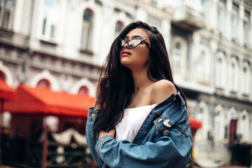 attractive stylish woman in sunglasses.Amazing joyful pretty girl with long brunette hair. posing outdoor. Close up fashion street stile portrait Model looking aside