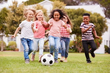 group of children playing football with friends in park