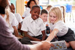 © Monkey Business - Male Teacher Reading Story To Group Of Elementary Pupils Wearing Uniform In School Classroom