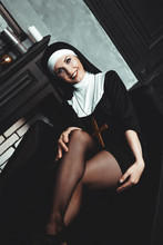 Sexy Nun Prays Indoor . Beautiful Young Holy Sister. Young Beautiful Nun With A Cross In A Robe In A Black Interior.