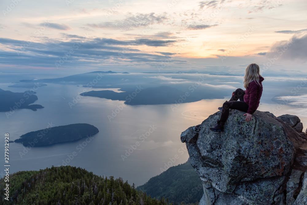 Adventurous Female Hiker on top of a mountain covered in clouds during a vibrant summer sunset. Taken on top of St Mark's Summit, West Vancouver, British Columbia, Canada. - obrazy, fototapety, plakaty 