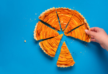 Woman hand taking a slice of sweet potato tart